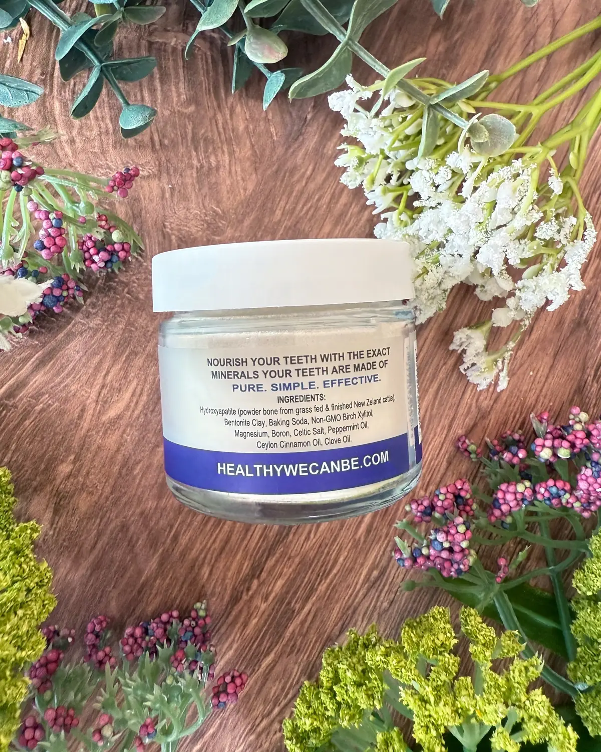 Re-mineralizing Tooth Powder photographed on wood with dried flowers