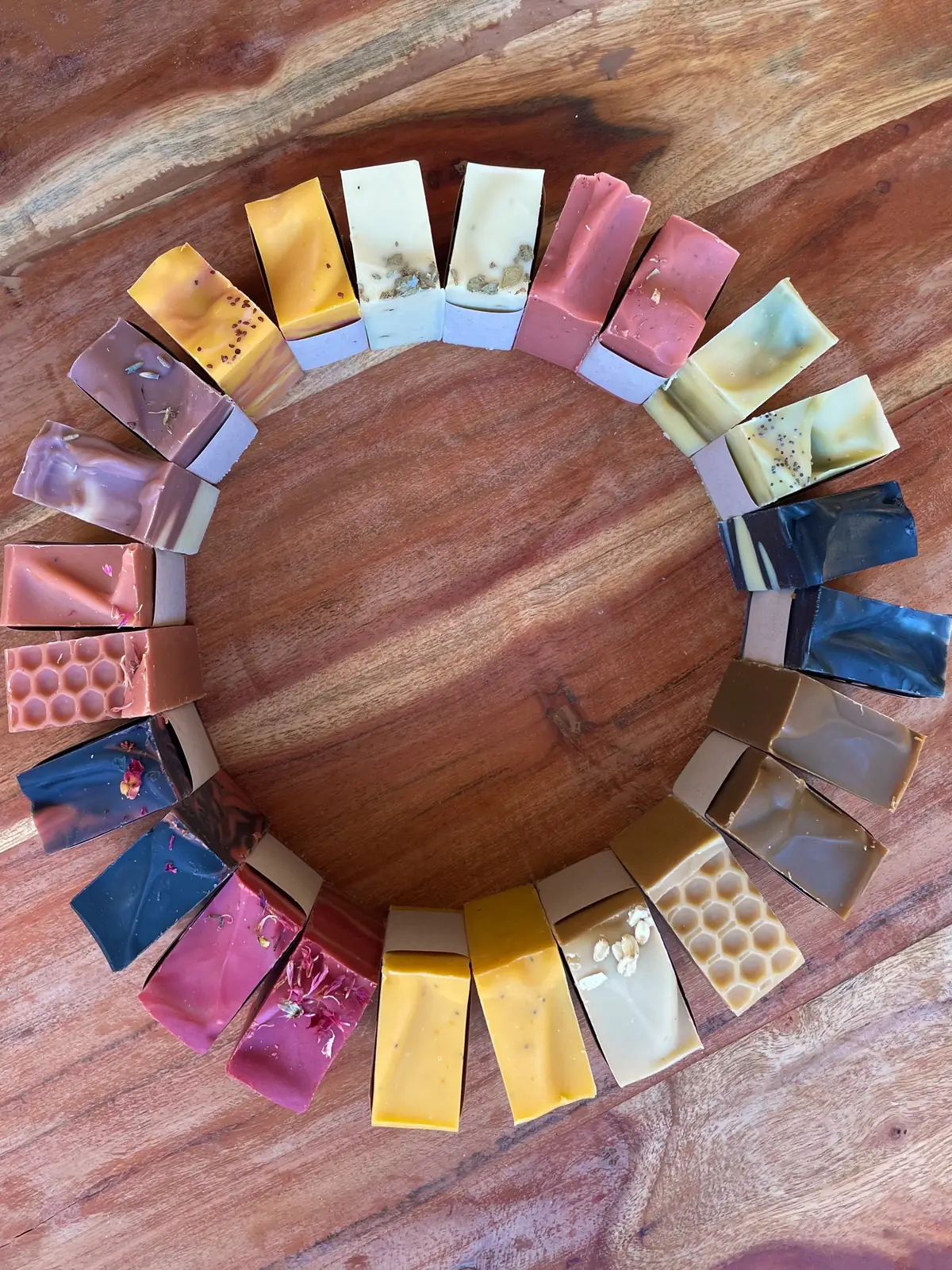 Thirty-four scents of Ashley Marie soap laid in a ring on a wooden board